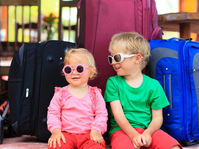 kids sitting on suitcases ready to travel